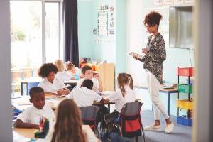 带着数码平板电脑的女老师在学校教室里教一群穿制服的小学生